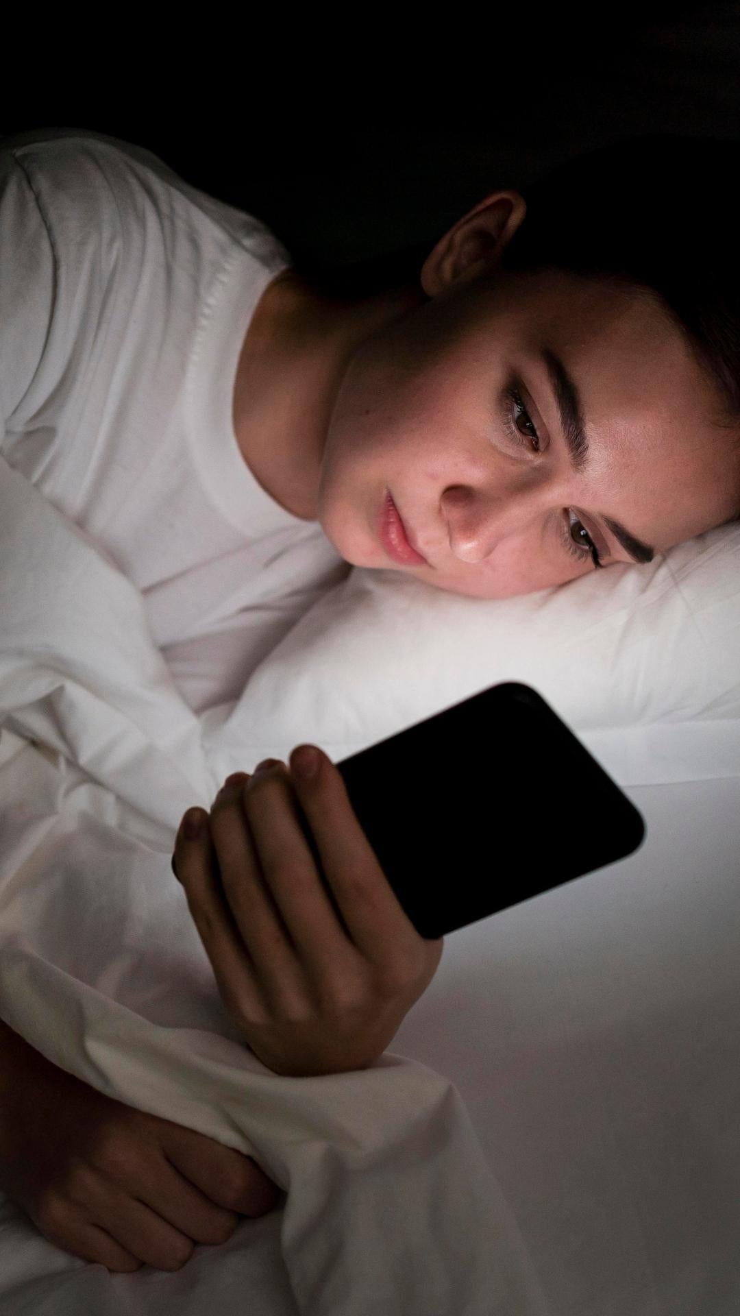 woman looking at her smartphone at night in bed