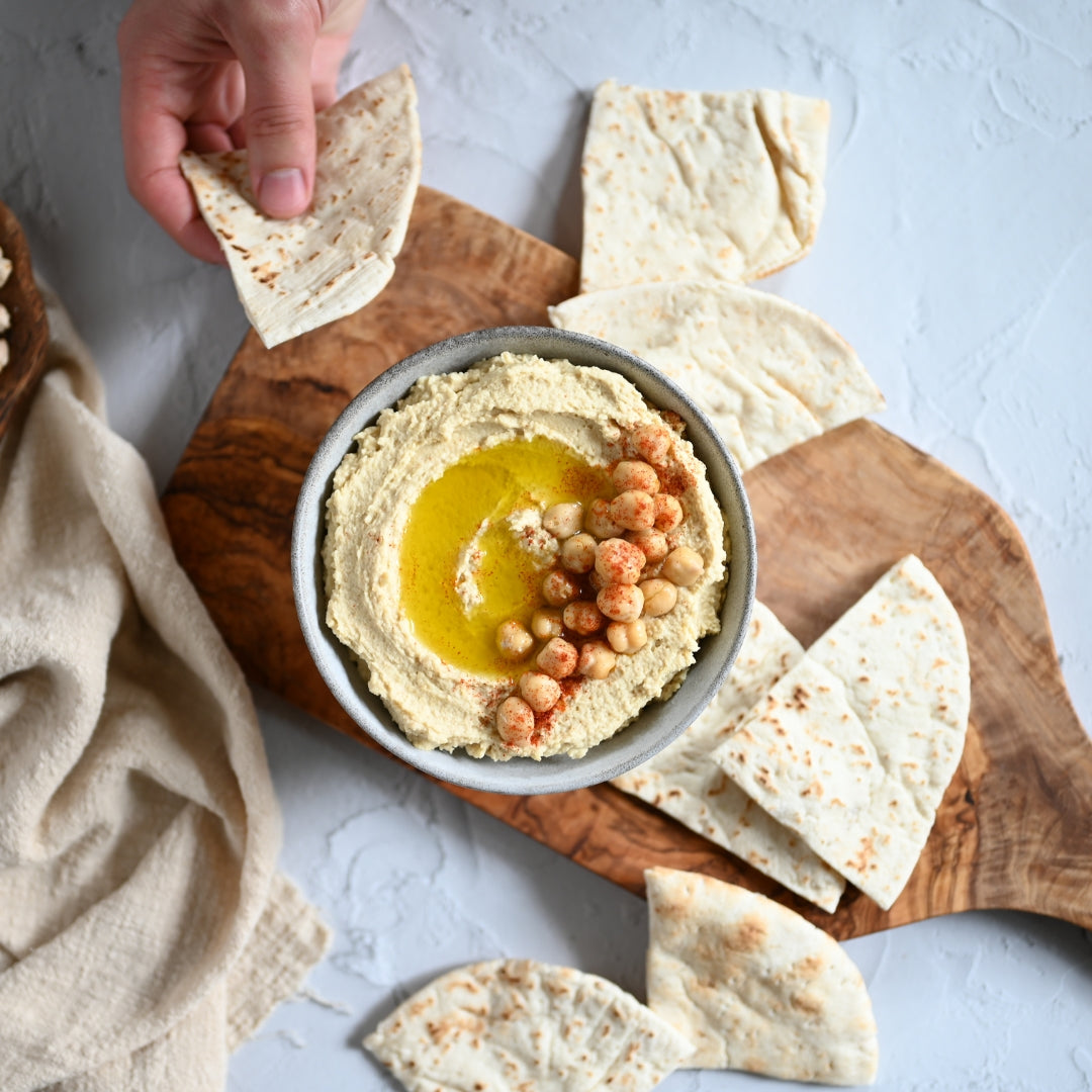 bowl of humus with crackers, hand holding cracker