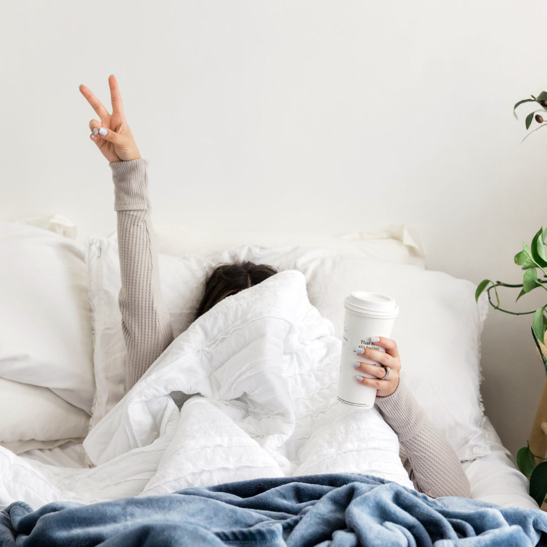 Happy woman in bed with coffee, white bed, white bedroom