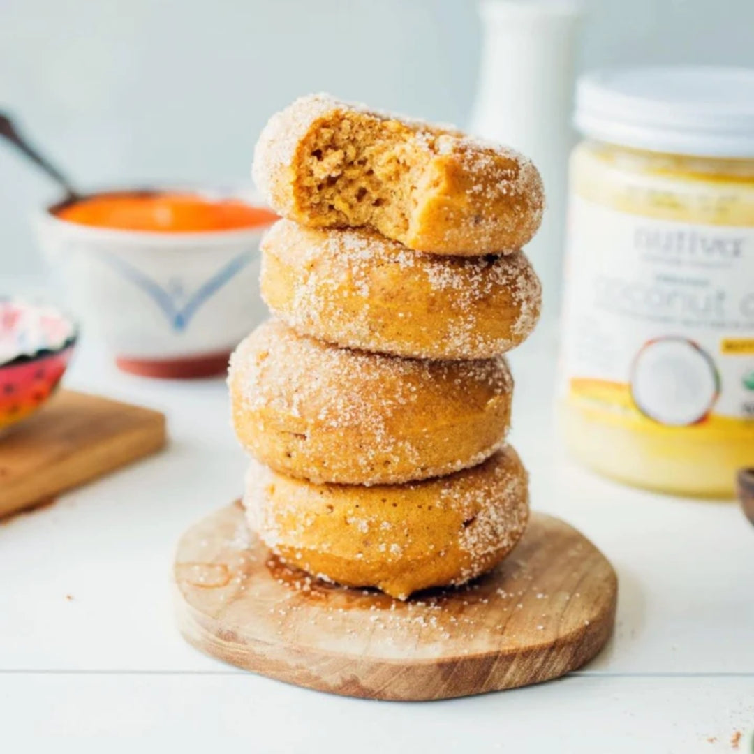 Donuts stacked on wooden plate, pumpkin puree, coconut oil