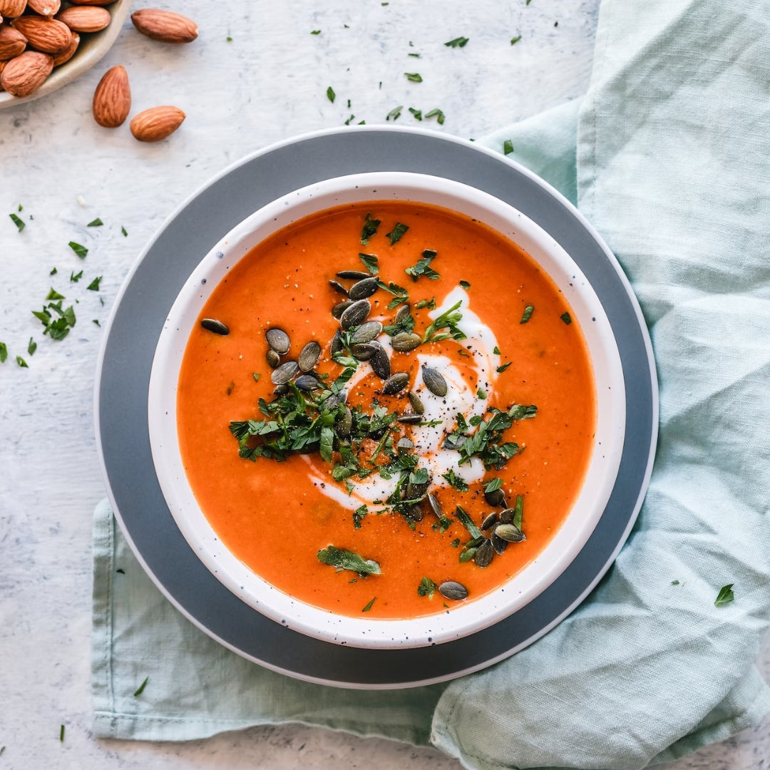 tomato soupe in white bowl, orange soupe,  grey table